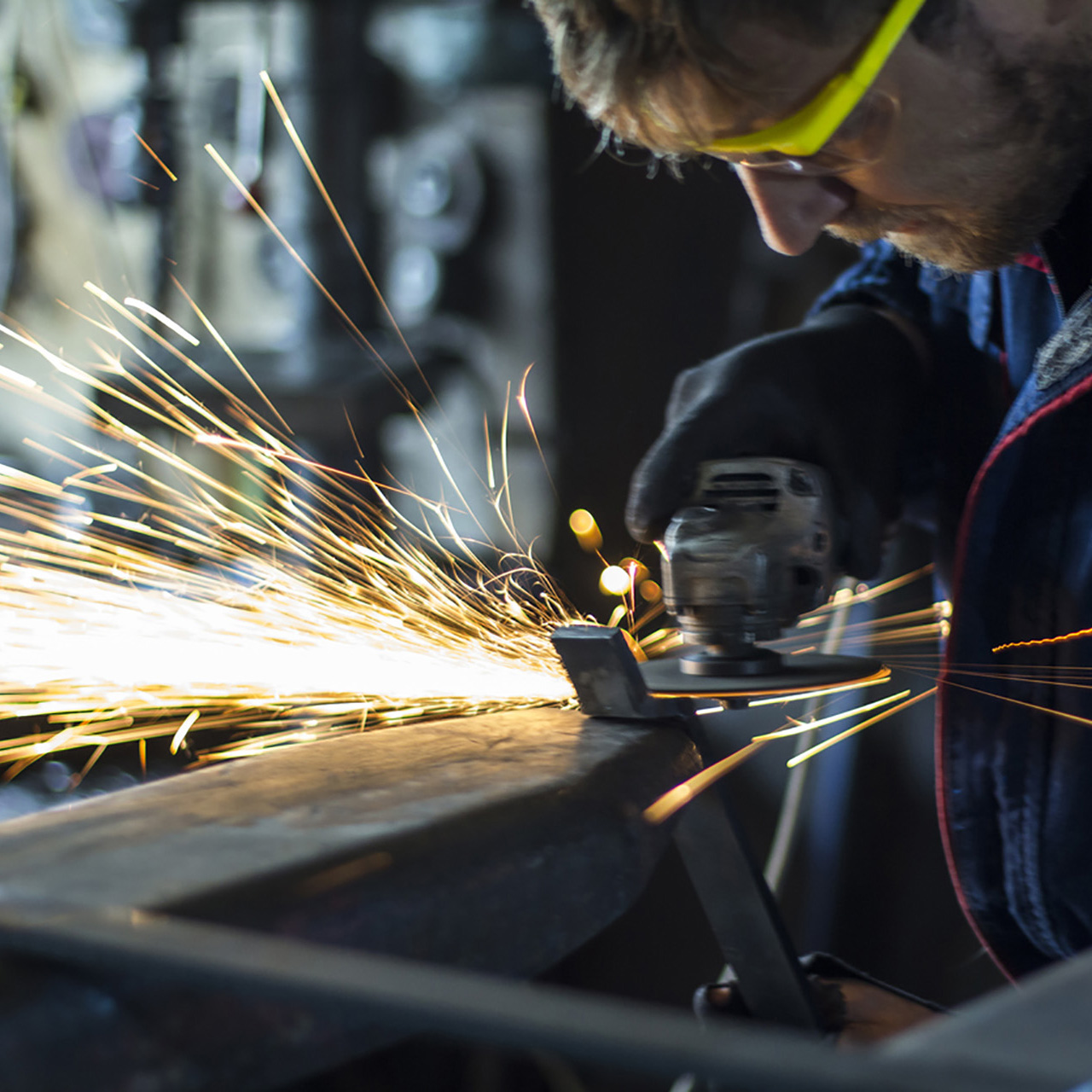 Factory worker using electric grinder in METAL INDUSTRY.